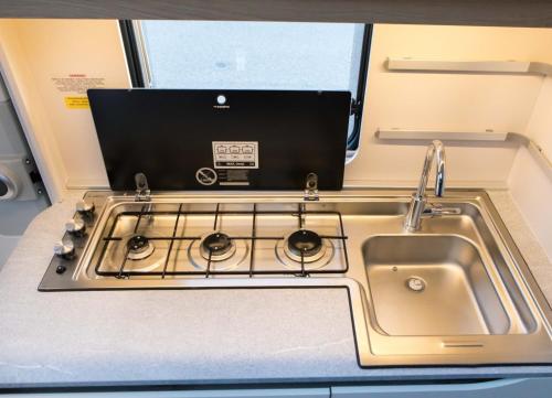 a kitchen with a sink and a stove at Przyczepa ADORA nad morzem in Rumia