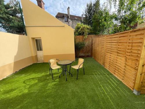 un patio con mesa y sillas en el césped en 2-Appartement RDC 28 m2 avec Jardin, en Mantes-la-Jolie