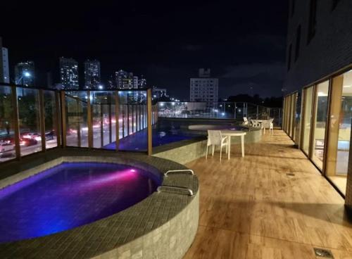 Un balcón de un edificio con piscina por la noche. en Ilusion hotel ponta negra Natal, en Natal