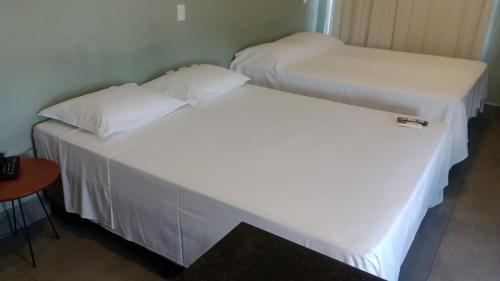 two beds in a room with white sheets and pillows at Ilusion hotel ponta negra Natal in Natal