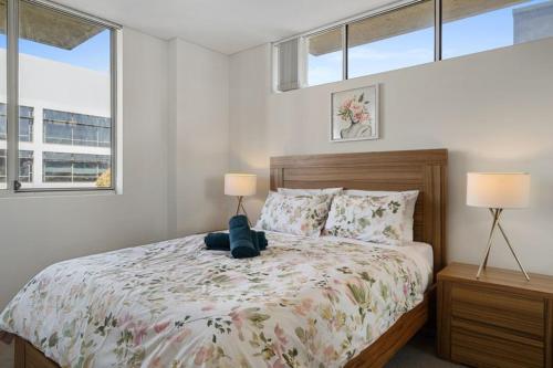 a bedroom with a bed with two lamps and two windows at 81M City View Abnb-Style 3BR Near Mascot Station with 2 FPKG in Sydney