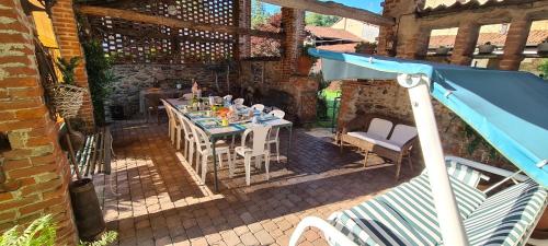 a patio with a table and chairs and a blue umbrella at L'Oasi Bed and Breakfast di Franco e Paola in San Martino Canavese