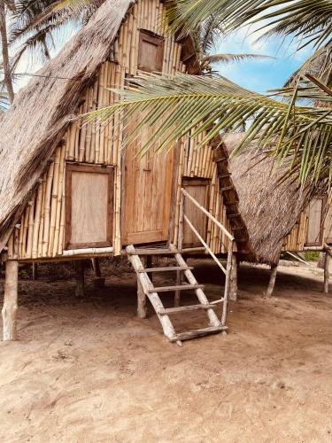 a small hut with a thatch roof and a ladder at Village Kirikou in Grand-Popo