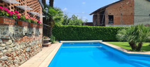 a swimming pool in a yard next to a brick building at L'Oasi Bed and Breakfast di Franco e Paola in San Martino Canavese