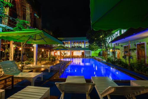 a swimming pool with chairs and umbrellas at night at Bamboo Hotel Phu Quoc in Phu Quoc