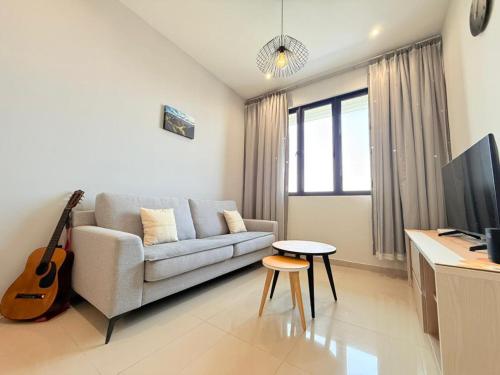 sala de estar con sofá y guitarra en Iconic Regency Service Residences - Bee's Home, en Bayan Lepas