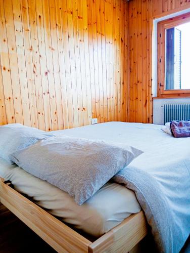 a bedroom with a bed with a wooden wall at Appartamento Lulù Polsa in Brentonico