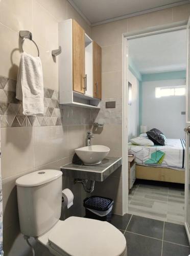 a bathroom with a toilet and a sink and a bed at EcoApartamentos Sunset Life in Providencia