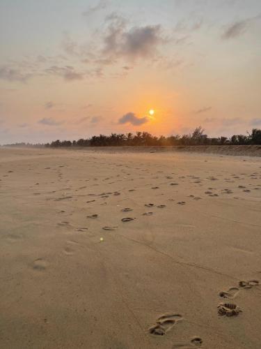 a sunset on the beach with footprints in the sand at Village Kirikou in Grand-Popo