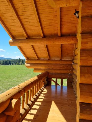 a wooden porch on a log cabin with a roof at Cabana dintre brazi Mărișel in Dealu Negru