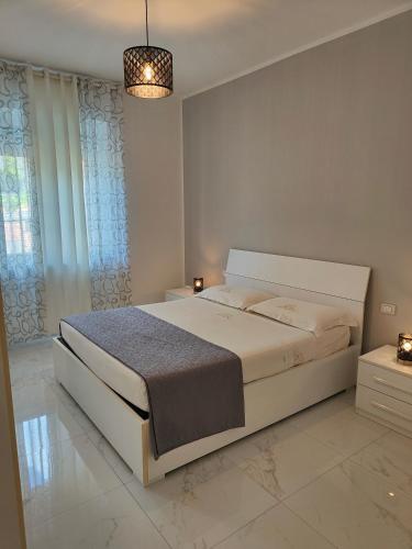 a white bedroom with a large bed and a chandelier at Alloggio comodo a Rapallo - Vicino al Mare in Rapallo