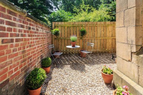 a patio with potted plants and a brick wall at The Motor House in Newcastle upon Tyne