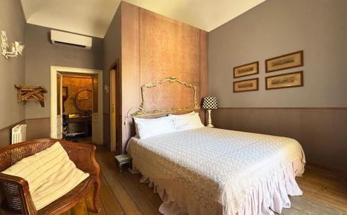 a bedroom with a bed and a chair at Il Salotto di Maria Pia in Siracusa
