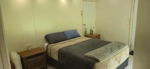 a small bedroom with a bed and two tables at DAINTREE RAINFOREST Private ROOM w-Ensuite In my 2 bdroom home in Cow Bay
