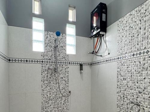 a bathroom with a shower and a television on the wall at Villa Ostara Kota Batu in Batu