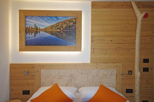 a bed with orange pillows and a picture on the wall at Hotel Aurai in Osteria Alpina