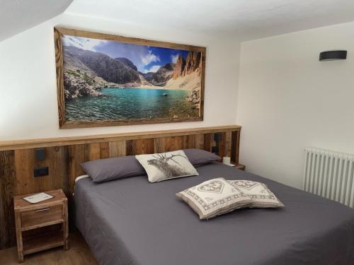 a bedroom with a bed with a picture on the wall at Il Sole delle Dolomiti in Campestrin