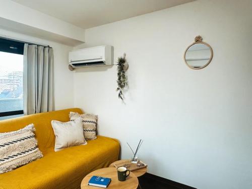 a living room with a yellow couch and a mirror at sakura 401 in Tokyo