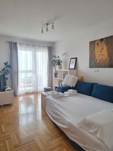 a living room with a large bed and a blue couch at Seaview apartman Vice in Trogir
