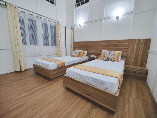 two beds in a room with wooden floors at Insara Cottage in Shillong