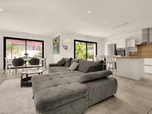 a living room with a gray couch and a kitchen at Nouvelle Villa Harmonia Piscine Proche Montpellier et Plages in Saint-Jean-de-Védas