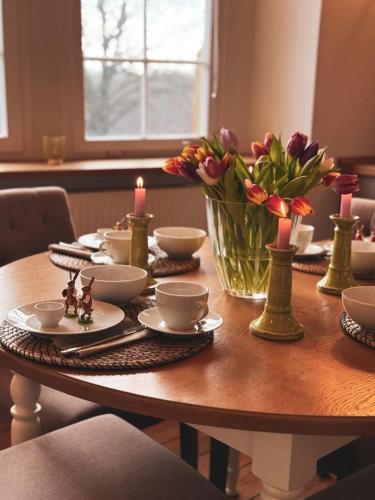 a wooden table with a vase of flowers and candles at Apartment Remise in Langenburg