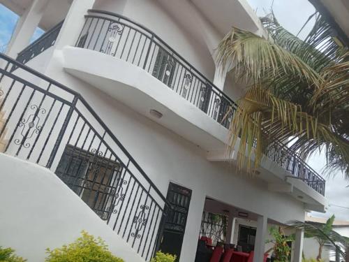 a white house with black railings and a balcony at Sukuta nema guest house in Sareh Mowndeh