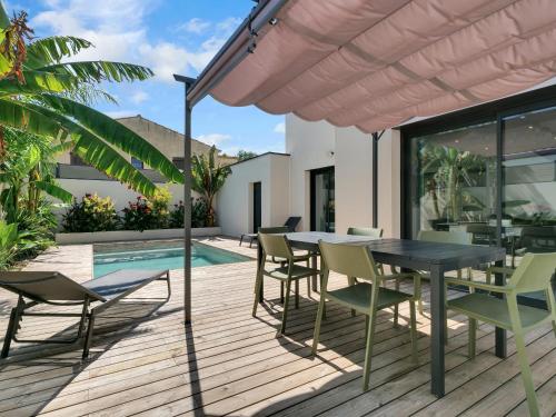 a patio with a table and chairs and a pool at Nouvelle Villa Harmonia Piscine Proche Montpellier et Plages in Saint-Jean-de-Védas