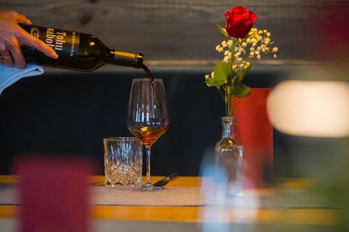 a person pouring wine into a glass with a rose at Boutique Hotel beim Lipp - Restaurant & Spa in Roßhaupten