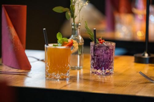 three cocktails sitting on a wooden table at Boutique Hotel beim Lipp - Restaurant & Spa in Roßhaupten