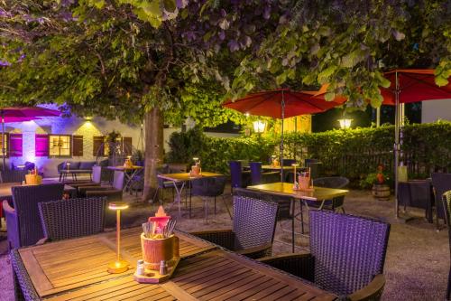 a restaurant with tables and chairs and umbrellas at night at Boutique Hotel beim Lipp - Restaurant & Spa in Roßhaupten