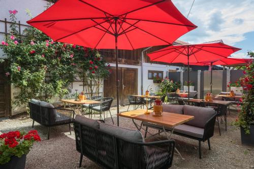 a patio with tables and chairs with red umbrellas at Boutique Hotel beim Lipp - Restaurant & Spa in Roßhaupten