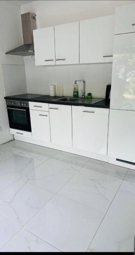 a white kitchen with white cabinets and a stove at Villa Lakeview Appartment in Leissigen