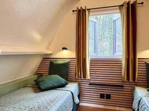 a bedroom with two beds and a window at Bosgeluk Durbuy in Durbuy