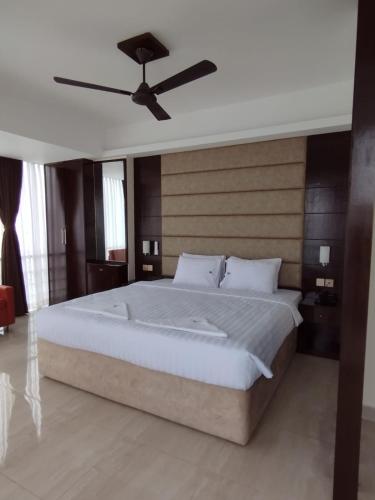 a bedroom with a large bed with a ceiling fan at White Park Hotel & Suites in Chittagong