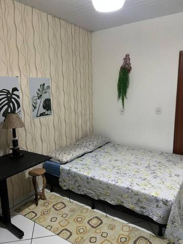 a bedroom with two beds and a table with a lamp at Suítes & Quartos Ponte do Imaruim in Palhoça