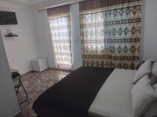 a bedroom with a large bed and two windows at Sukuta nema guest house in Sareh Mowndeh