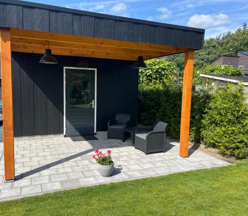 a black building with two chairs and a patio at B&B de Bosrand in Emmen