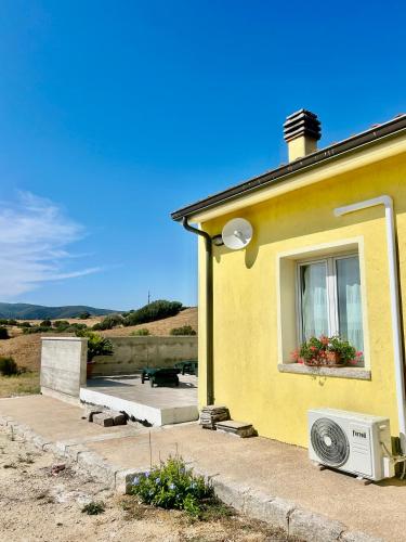 a yellow house with a window and a microwave at San Leonardo Country House in Calangianus