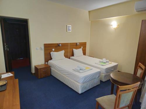 a hotel room with two beds and a table at Hotel Saint Nedelya in Kolarovo