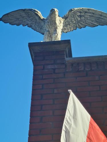 an eagle statue next to a brick wall with an american flag at Leśna Polana- Kompleks Domków Mieszkalnych in Kamionka