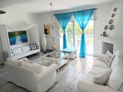 a living room with white furniture and blue curtains at OASIS VILLA in Litochoro