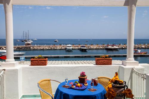 a table on a balcony with a view of a harbor at Hotel La Sirenella in Ischia