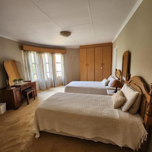 a large bedroom with two beds and a desk at Simply Rooted Cottage in Piet Retief