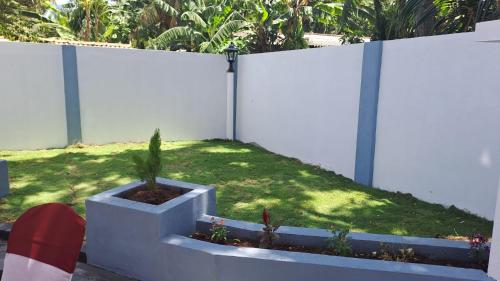 a white fence with a potted plant in a yard at Pooranam Vacation Home in Jaffna