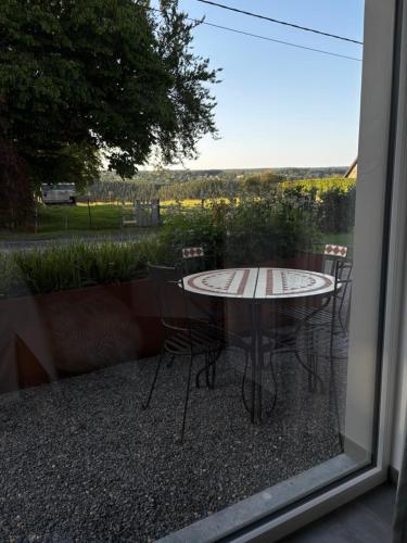 a table and chairs on a patio with a window at La Halte in Malmedy