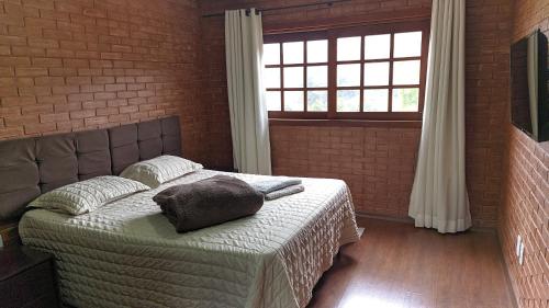 ein Schlafzimmer mit einem Bett mit Kissen und einem Fenster in der Unterkunft Casa ao lado da cervejaria 3 Santas no Caravaggio in Santa Teresa