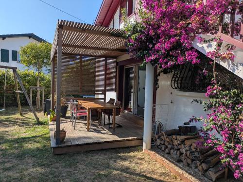 une terrasse en bois avec une table et quelques fleurs dans l'établissement VILLA with swimming pool near Ocean and Forest, à Anglet
