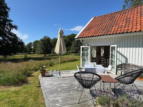 a patio with an umbrella and chairs on a deck at Idyllically nice house on Bjärehalvön, Torekov! in Båstad