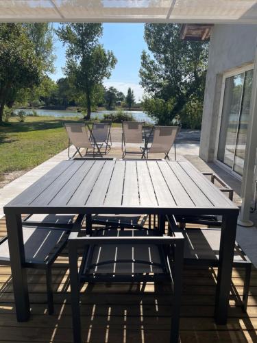 - une table de pique-nique en bois avec des chaises sur la terrasse dans l'établissement l'Héberge du Lac d'Isachris (Médoc), à Queyrac